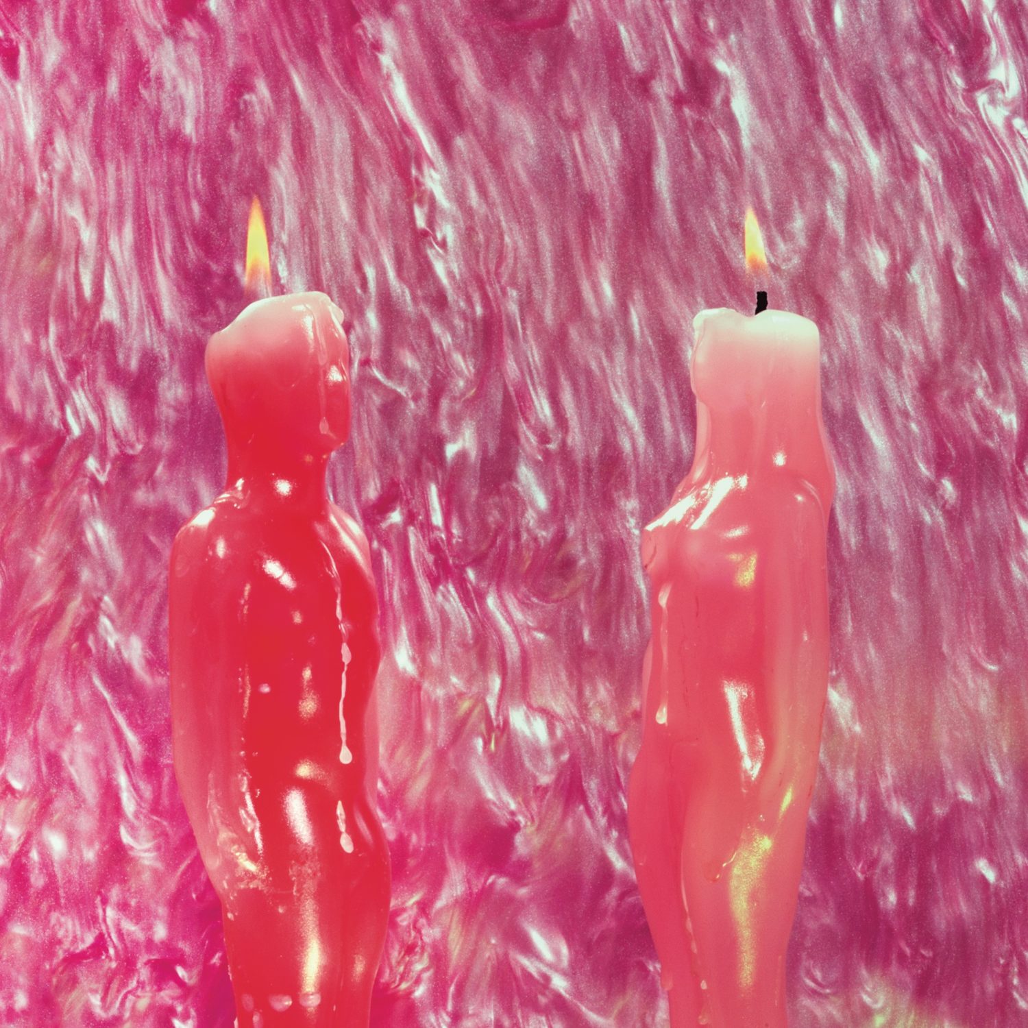 Two pink candles burning. One is a man one and is a woman. 